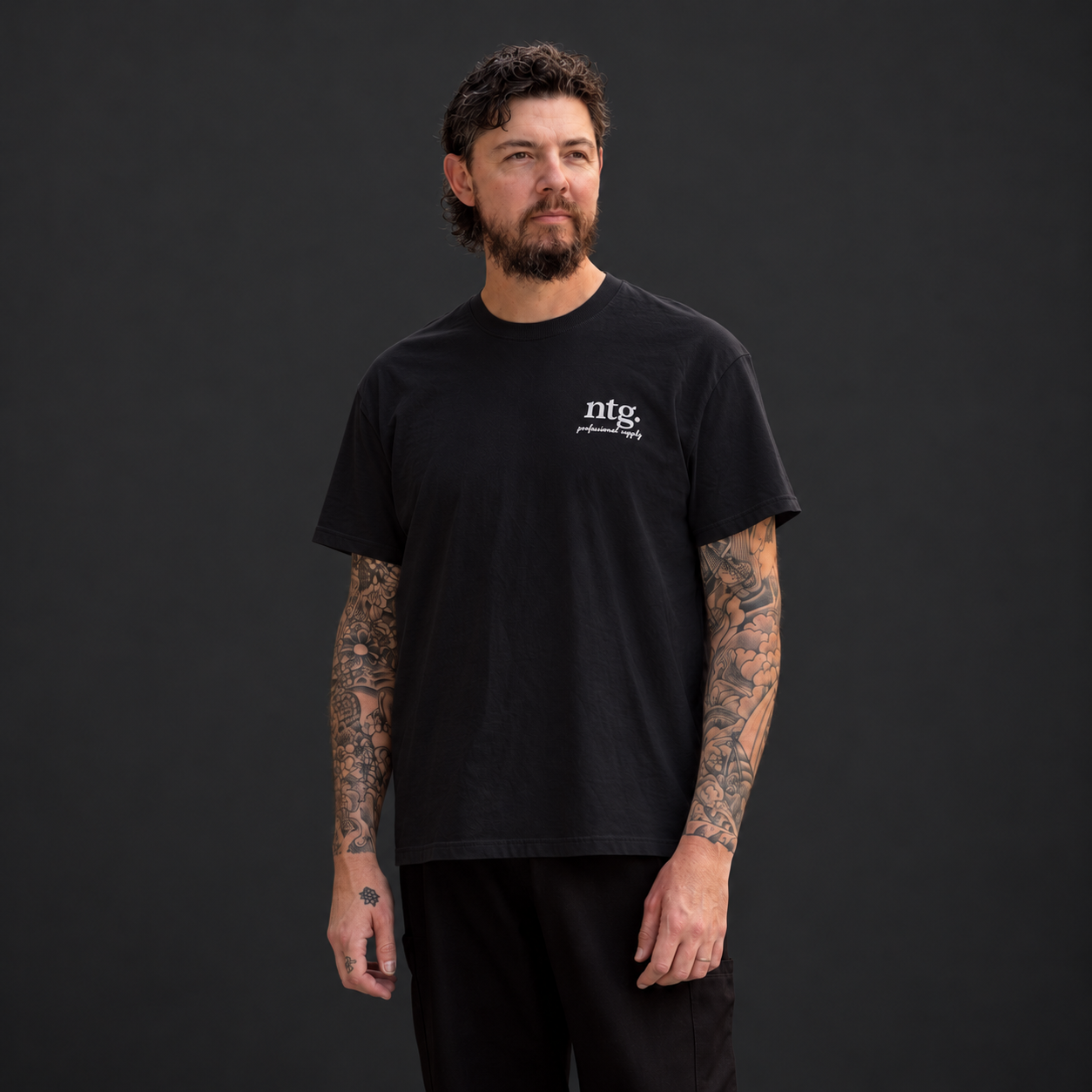 Front view of a model wearing a black Chart’d T-shirt with a small white ntg. chest print.