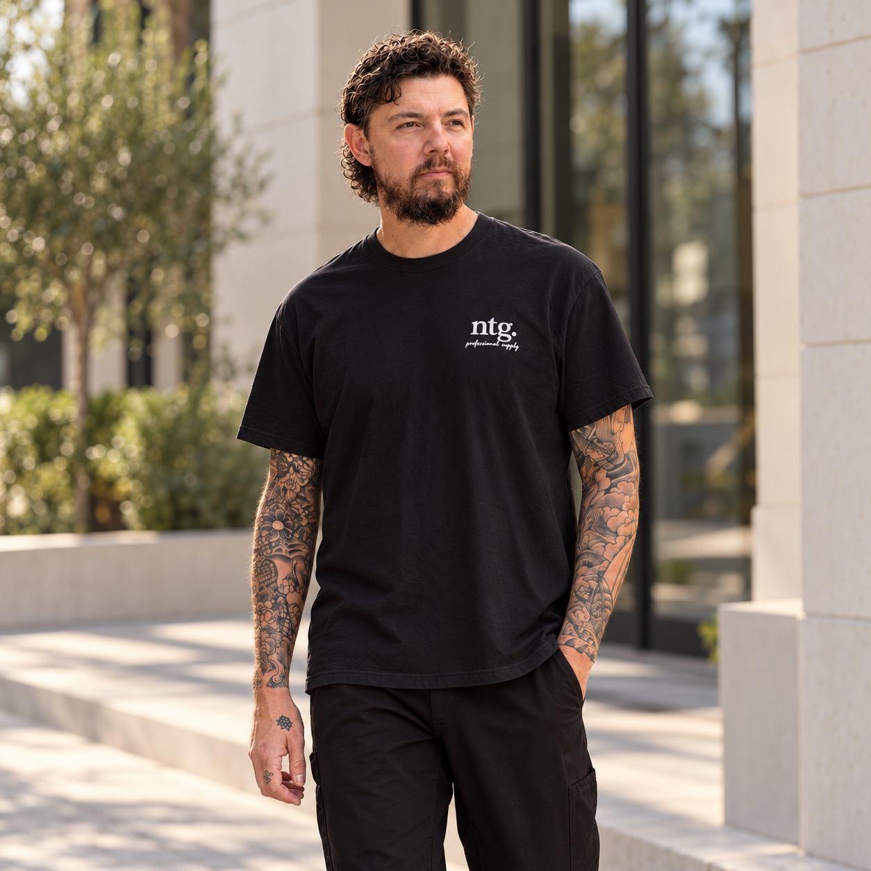 Model wearing a black NTG Chart’d T-shirt outside a modern building.