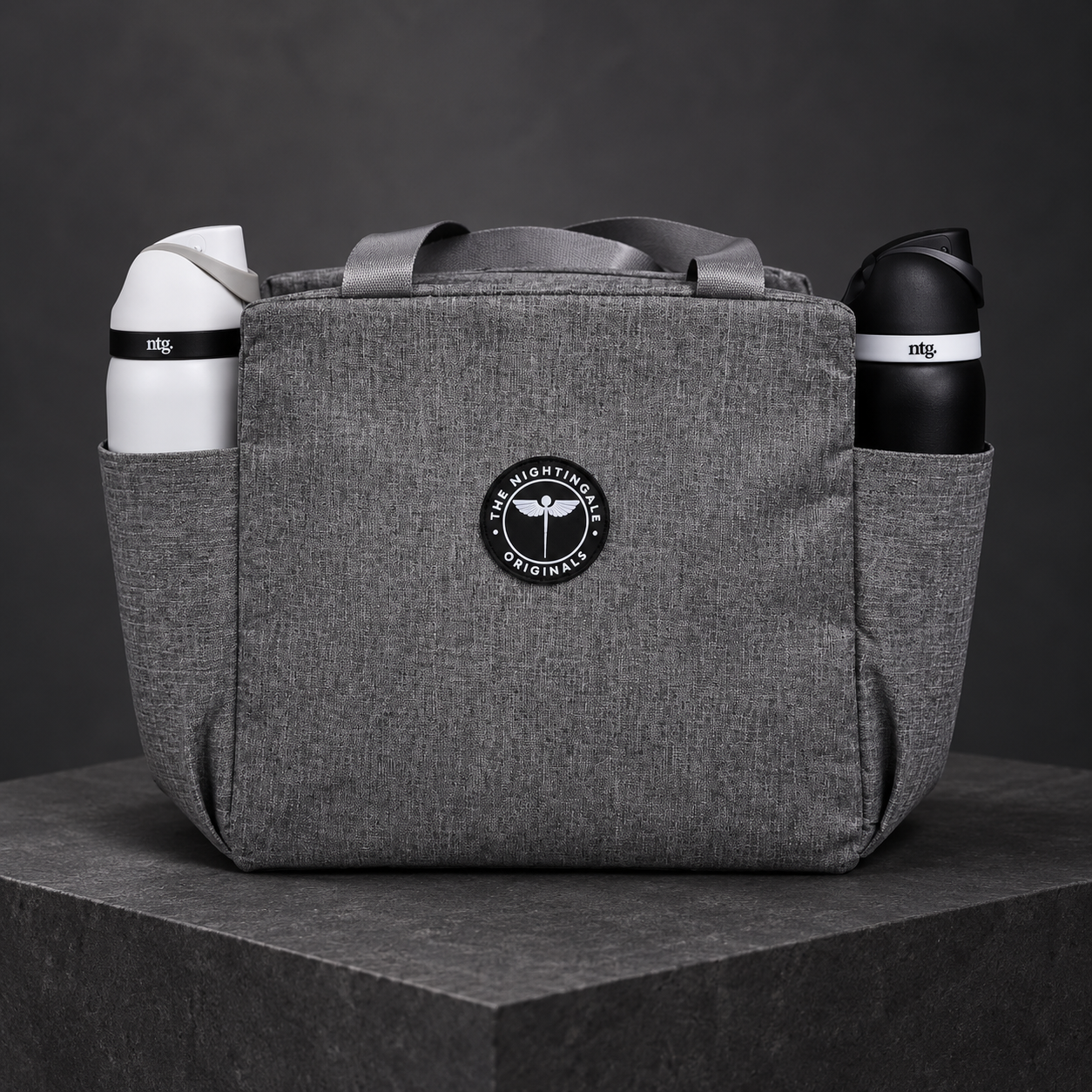 Gray Famish’d lunch bag with white and black NTG tumblers in its side pockets.