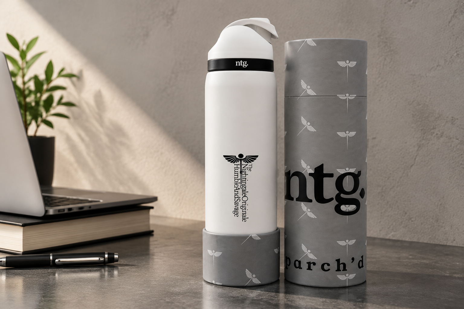 White Parch’d tumbler and gray cylindrical packaging beside a laptop on a desk.
