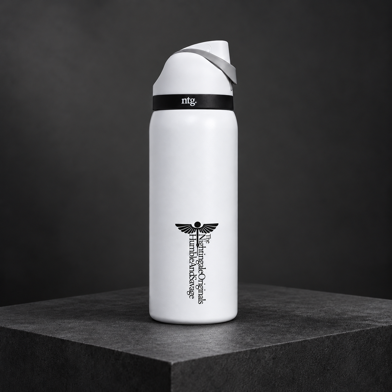 White Parch’d flip-top tumbler with a black medical emblem on a charcoal stone plinth.