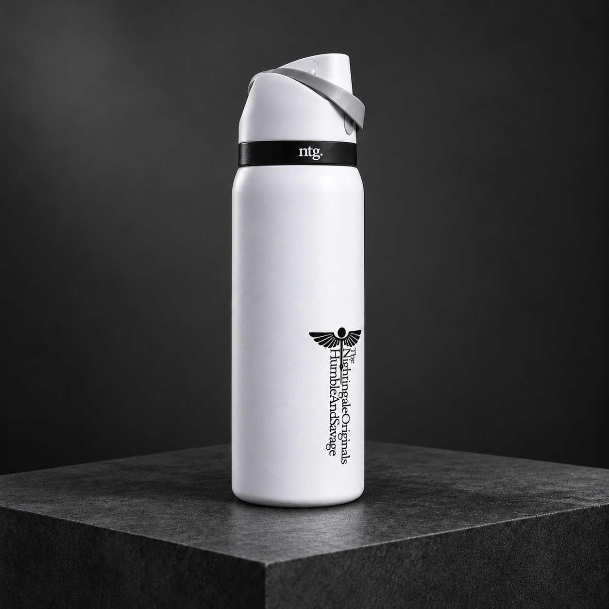 Three-quarter view of a white Parch’d tumbler with a gray flip-top lid on dark stone.