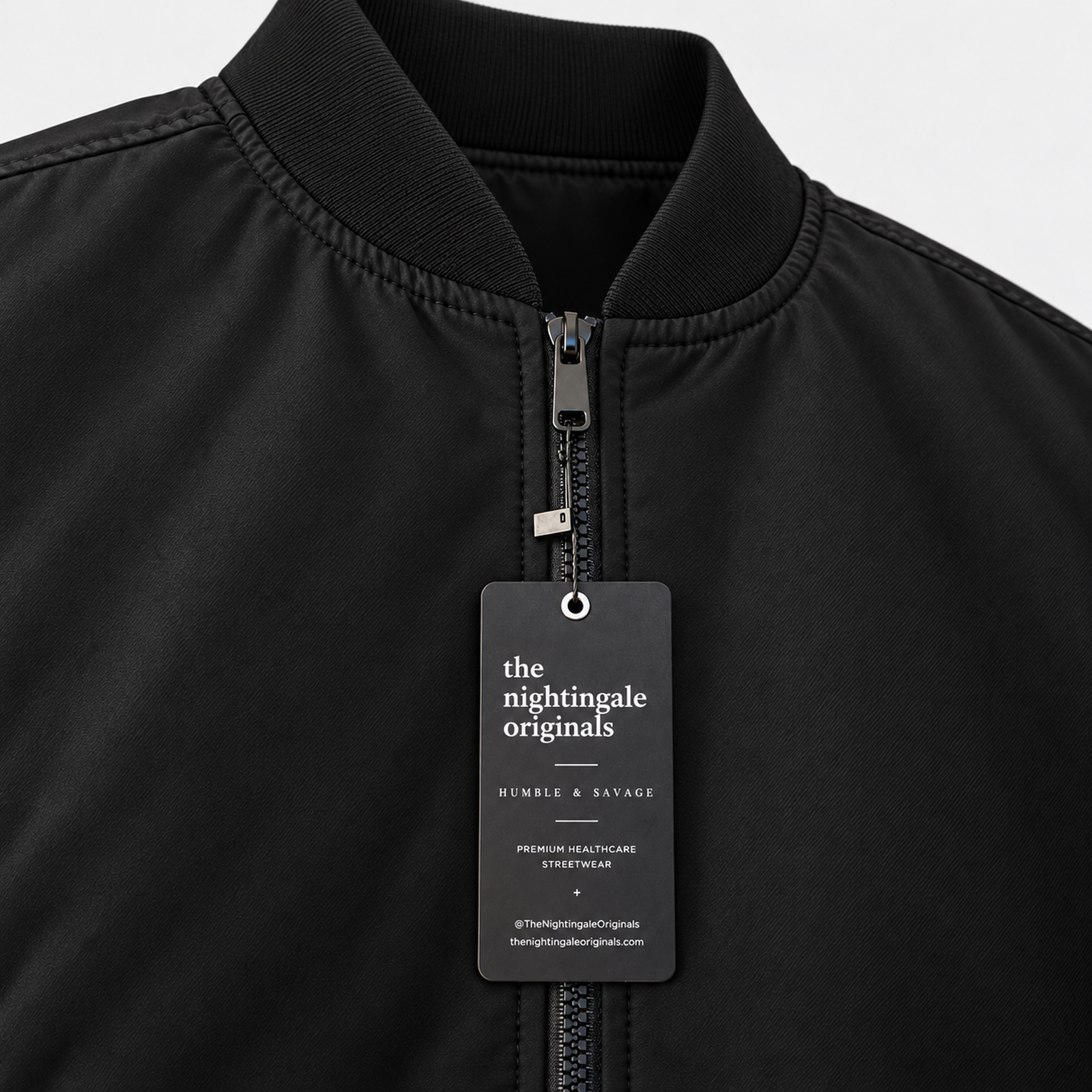Close-up of a black Venous bomber jacket collar, front zipper and Nightingale Originals hangtag.